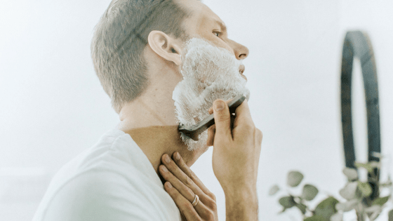 a man shaving and working on his grooming regimen