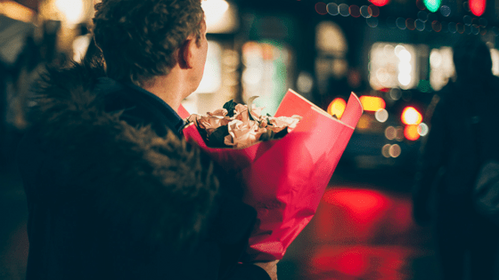 a man waiting bringing flowers and waiting for his date
