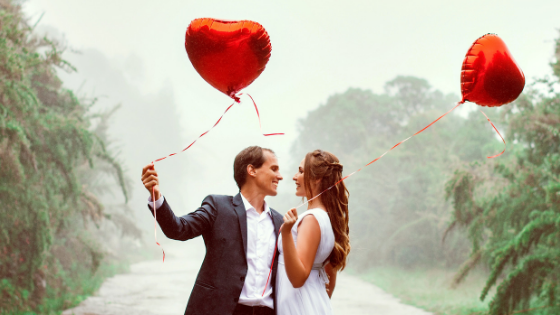 a couple holding heart balloons